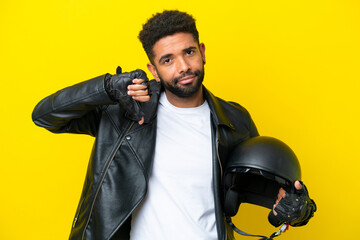Young Brazilian man with a motorcycle helmet isolated on yellow background showing thumb down with...