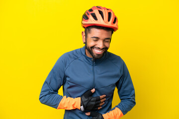Young cyclist Brazilian man isolated on yellow background smiling a lot