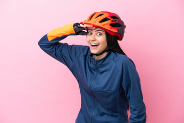 Teenager cyclist girl isolated on pink background doing surprise gesture while looking to the side