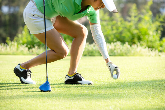 Asia sporty woman put golf ball on tee with club in golf course on evening on time for healthy sport. Banner and copy space for text.  Lifestyle and Sport Concept