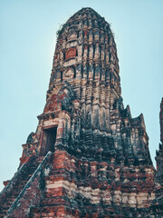 An ancient brick temple with a steep staircase leading up to a central tower, set against a clear blue sky. At Ayutthaya, Thailand. 