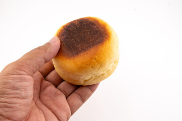 A close-up shot shows a hand holding a single, round bun against a plain white background. 