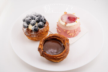 A close-up shot captures three delectable mini pastries arranged on a white plate. 