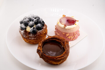 A close-up shot captures three delectable mini pastries arranged on a white plate. 