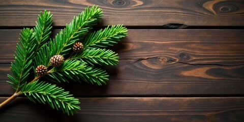 A lush evergreen bough with miniature cones rests on a dark wood surface, offering a rustic and natural holiday aesthetic.