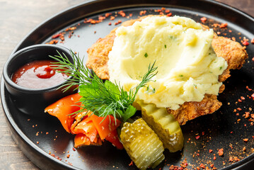 A delicious plate featuring fried chicken with creamy mashed potatoes, garnished with fresh herbs,...