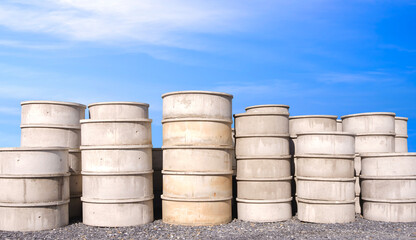 Group of concrete well rings with different diameters stacked on the ground outside of hardware store, front view with copy space