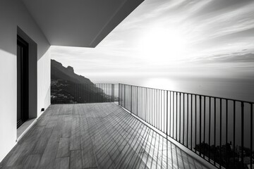Fototapeta premium Modern balcony overlooking a serene coastal landscape with mountains in the background.