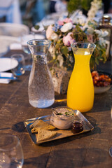 Set table at a banquet with carafes of fresh water and orange juice, flowers and hors d'oeuvres.