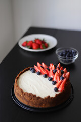 freshly baked classic cheesecake with strawberries and blueberries