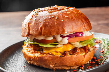 A mouthwatering burger with a sesame seed bun, layered with melted cheese, fresh lettuce, tomato, and mayonnaise. The rich colors and textures create an appetizing presentation.