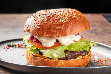 A delicious burger with a sesame seed bun, featuring a juicy beef patty, fresh lettuce, tomato, and creamy mayonnaise. The appealing layers create a mouthwatering presentation.