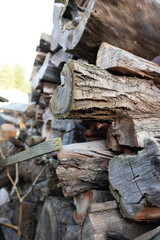 Close-up image of a neatly stacked pile of firewood logs, showcasing the natural texture of weathered wood and bark
