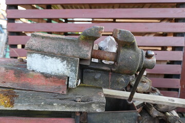 Close-Up of Old Rusty Metal Bench Vise on Wooden Surface
