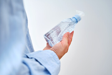 An unrecognizable person in blue clothes holds a bottle of hyaluronic micellar gel for washing.