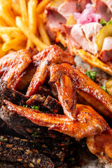 A tantalizing close-up of smoky BBQ chicken wings, fall-off-the-bone ribs, and crispy fries. The vibrant colors and textures create an irresistible feast for meat lovers.