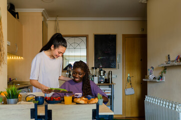 Two women sharing a moment of intimacy while having breakfast and using a smartphone in their...