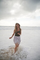 Joyful Woman Running Through Ocean Waves on Beach
