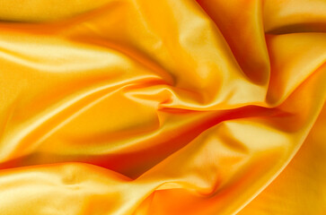 Obraz premium Macro shot of golden silk cloth draped in gentle folds with a polished satin finish.