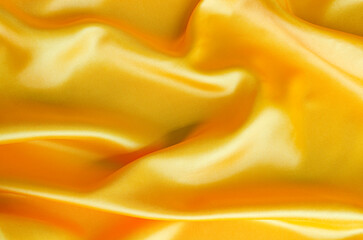 Close up of glossy yellow satin material with smooth surface and folds. Suitable for design and wallpaper background