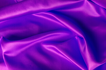 Top view of shiny maroon satin cloth with radiant surface highlights and fine woven texture in natural folds