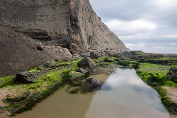 Magoito beach cliffs reflecting on a small stream at sintra, portugal
