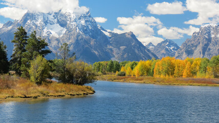 Lake with trees in autumn colors and snowy mountains in the background 