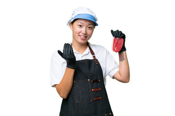 Young caucasian woman wearing an apron and serving fresh cut meat over isolated background inviting to come with hand. Happy that you came
