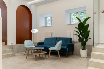 a large stylish lobby in a luxury house or hotel. orange sofas and armchairs, tables, large glass chandeliers. A large room with white walls and a dark floor.