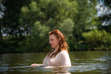 Mature woman enjoying a refreshing swim in a serene summer river