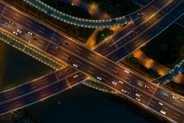 Aerial view of a busy road junction during nighttime with illuminated highways and moving vehicles.