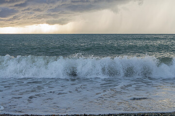 Waves Crash on the Shore Under a Dramatic Sky at Sunset