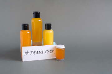The concept of the danger of products containing trans fats. Containers filled with various trans fats, close-up on a dark background