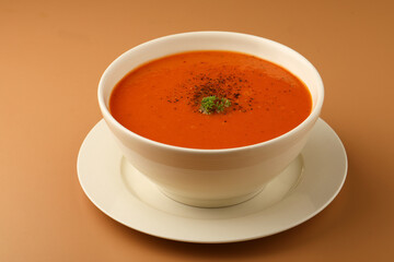bowl of tomato soup with parsley on brown background