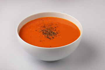 bowl of tomato soup with parsley on white background