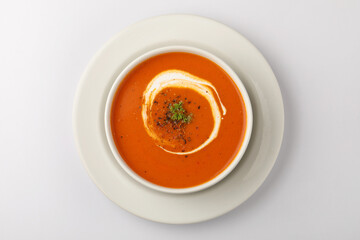 bowl of tomato soup with parsley on white background