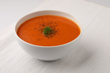 bowl of tomato soup with parsley on white background