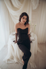 Elegant woman in black outfit sitting gracefully near candles