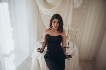 Thoughtful woman in chic black dress in aesthetic studio