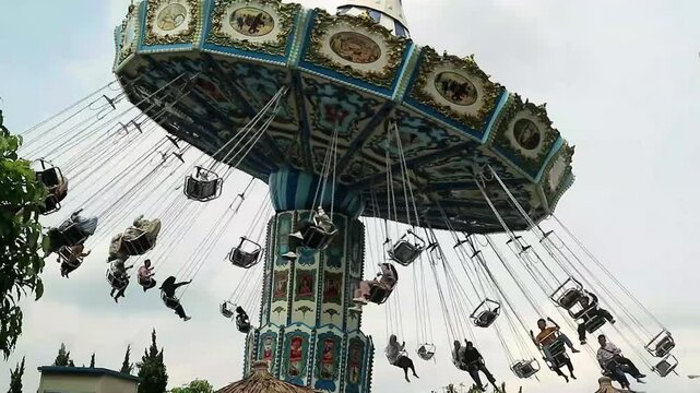 On the merry-go-round. Flight through the air rides. Animal swinger or Chairoplane, Exciting rides and games at amusement park for family, Concept of equilibrium circular motion in a rotation