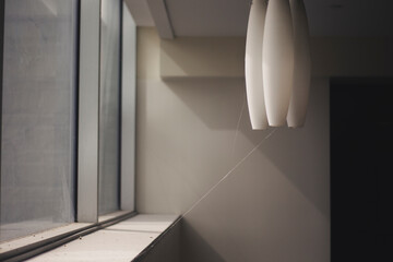 Obraz premium Soft morning light casting shadows through dusty windows and modern pendant lights. Minimal interior corner catching spider webs.