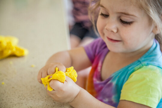 Little girl squishing playdough in her fingers