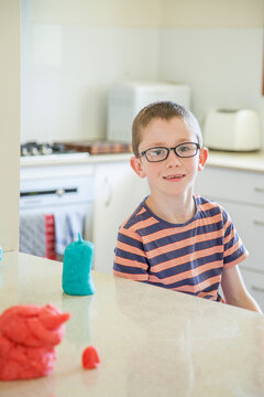 Eight year old boy making play dough creations inside