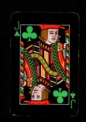 A black vintage playing card in the suit of clubs isolated on a black background.