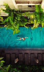 Aerial view of Active man, swimming in pool, drone view from above, Bali villa, tropical vacation, holiday on island hotel resort	
