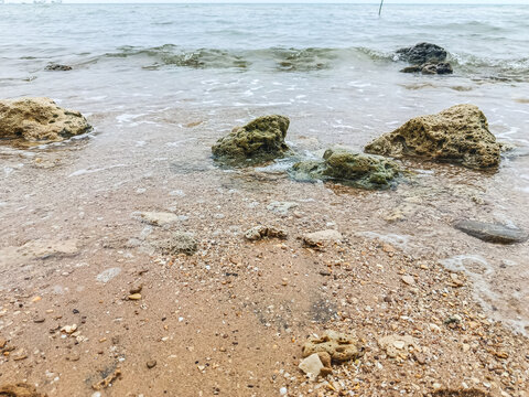 Tranquil Rocky Seaside with Overcast Sky and Gentle Waves