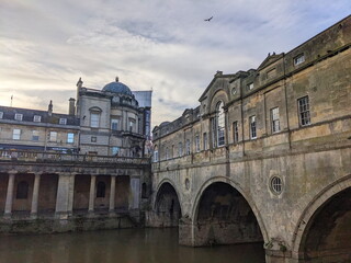 Pulteney Bridge spans the River Avon, framed by Victoria Art Gallery under a dramatic cloudy sky
