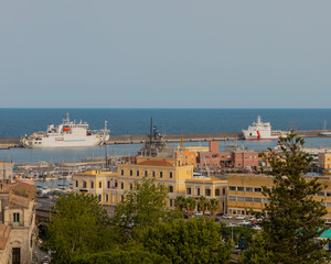 Aerial view of ancient Sicilian rooftops with terracotta tiles, overlooking the sparkling Mediterranean Sea and coastal landscape