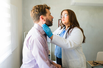 Female physician checking male patient's neck during medical consultation in well-lit clinical setting