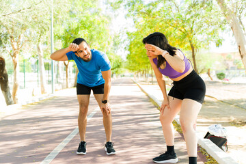Tired hispanic couple resting after running on track